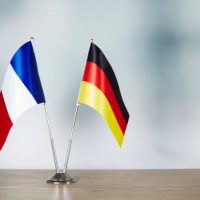 French and German flag standing on the table with defocused background